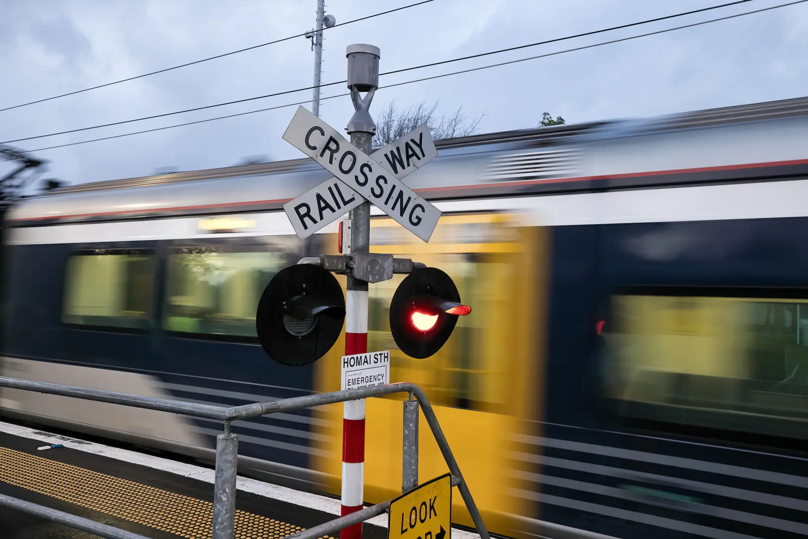 Train zooming past a level crossing sign