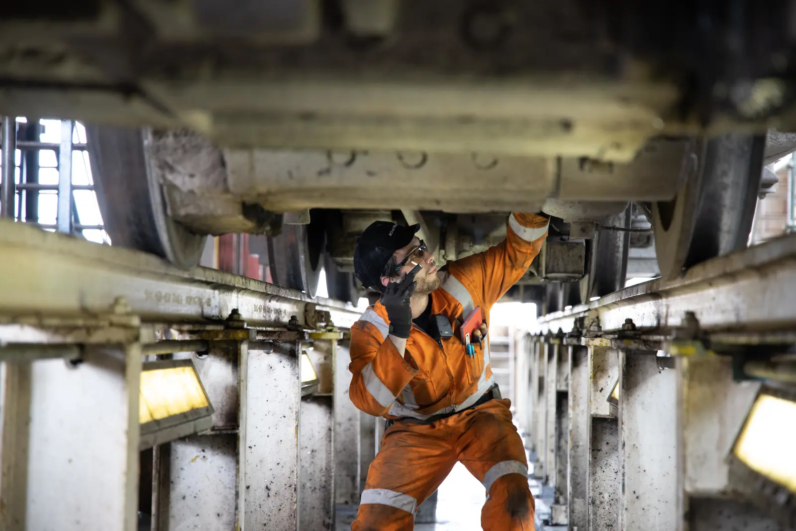 Man in high-vis working on underside of train